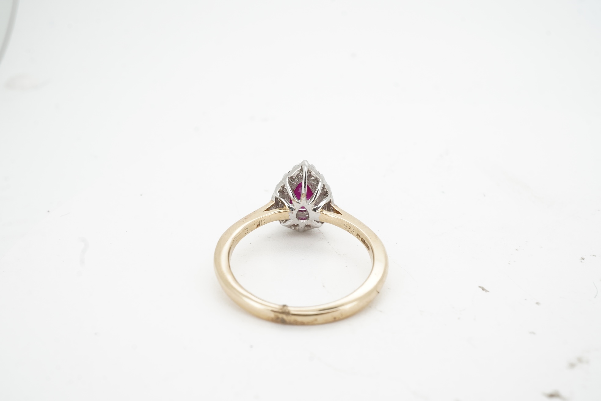 A ruby and diamond cluster ring, claw-set with a pear-shaped ruby weighing approximately 0.60 carats, within a border of brilliant-cut diamonds totalling approximately 0.42 carats, mounted in 14ct gold, size N, British h